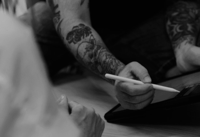 A tattooer discussing sketches and pricing with his client.