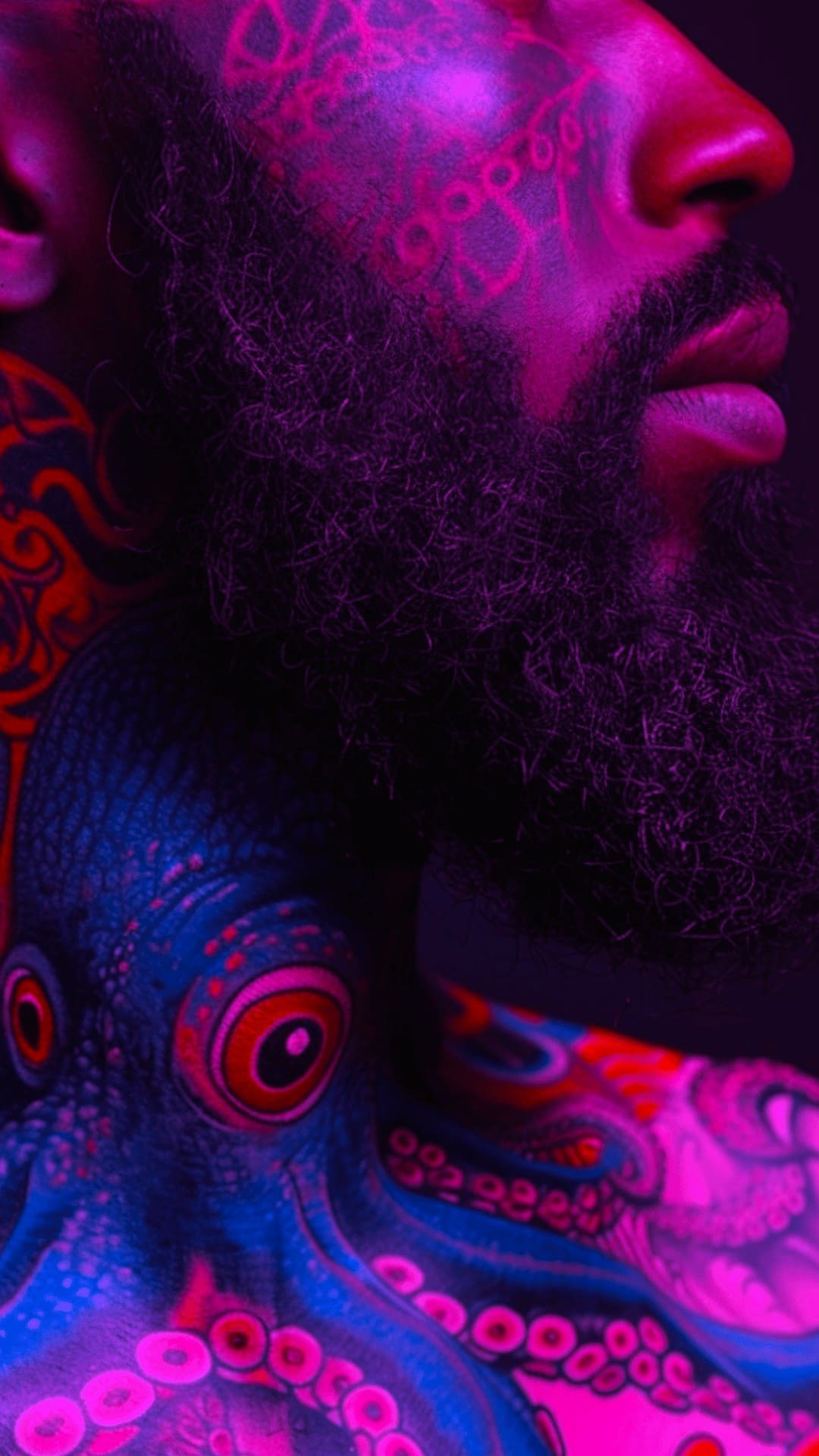 Close-up of a heavily tattooed man's face and neck, featuring intricate octopus tattoo design.