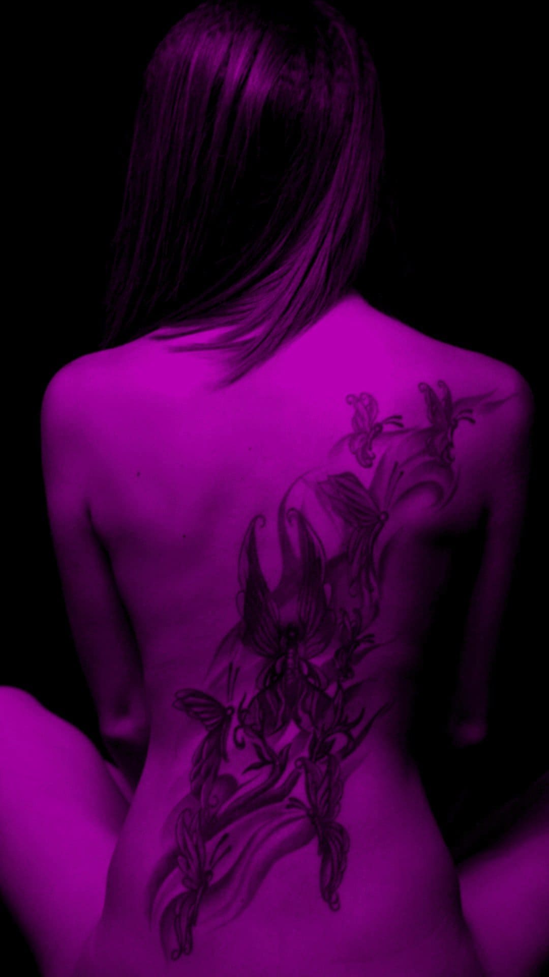 A young woman with a fineline abstract back tattoo.